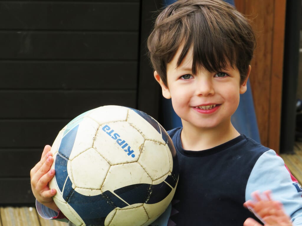 Nursery child playing with a football