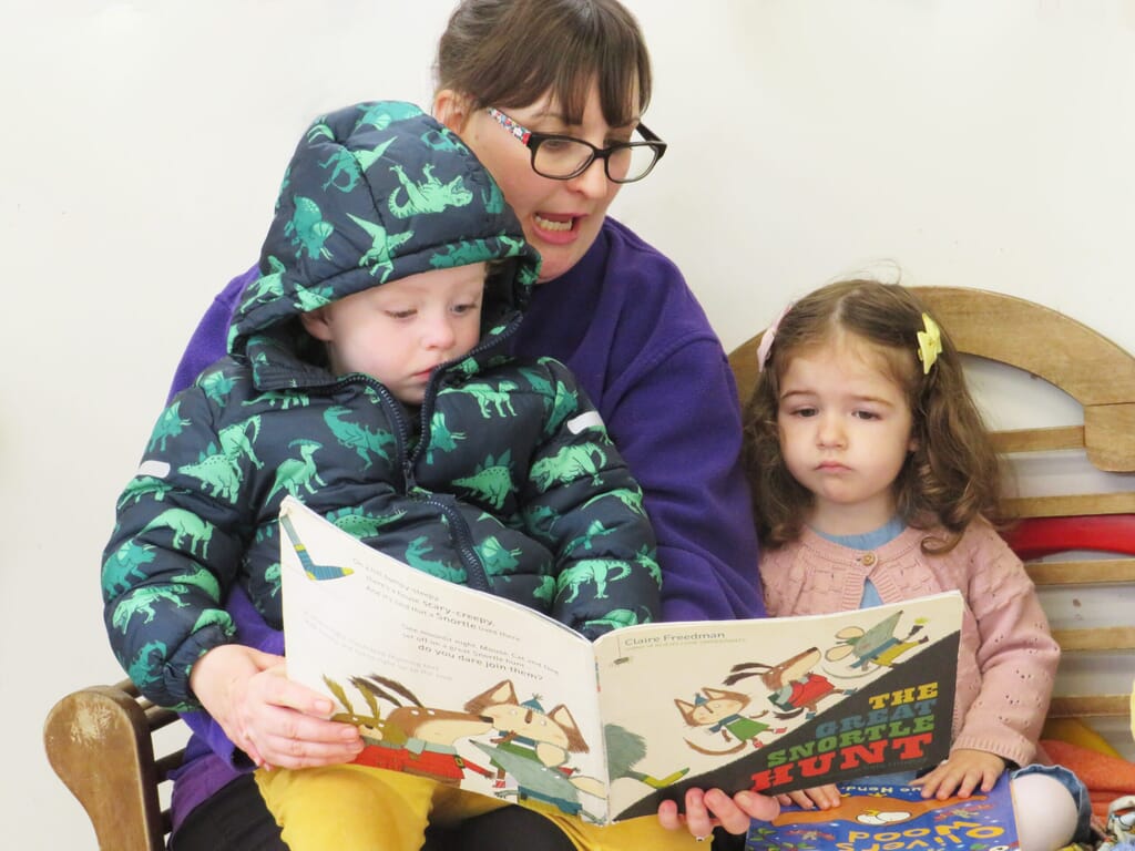Nursery carer reading with nursery children