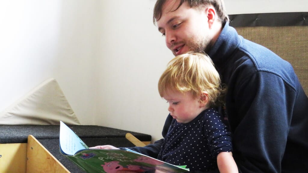 Nursery carer reading with nursery child