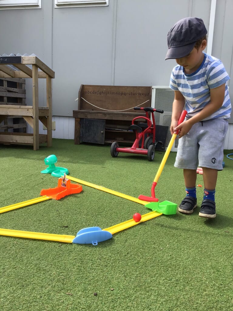 Nursery child playing mini golf