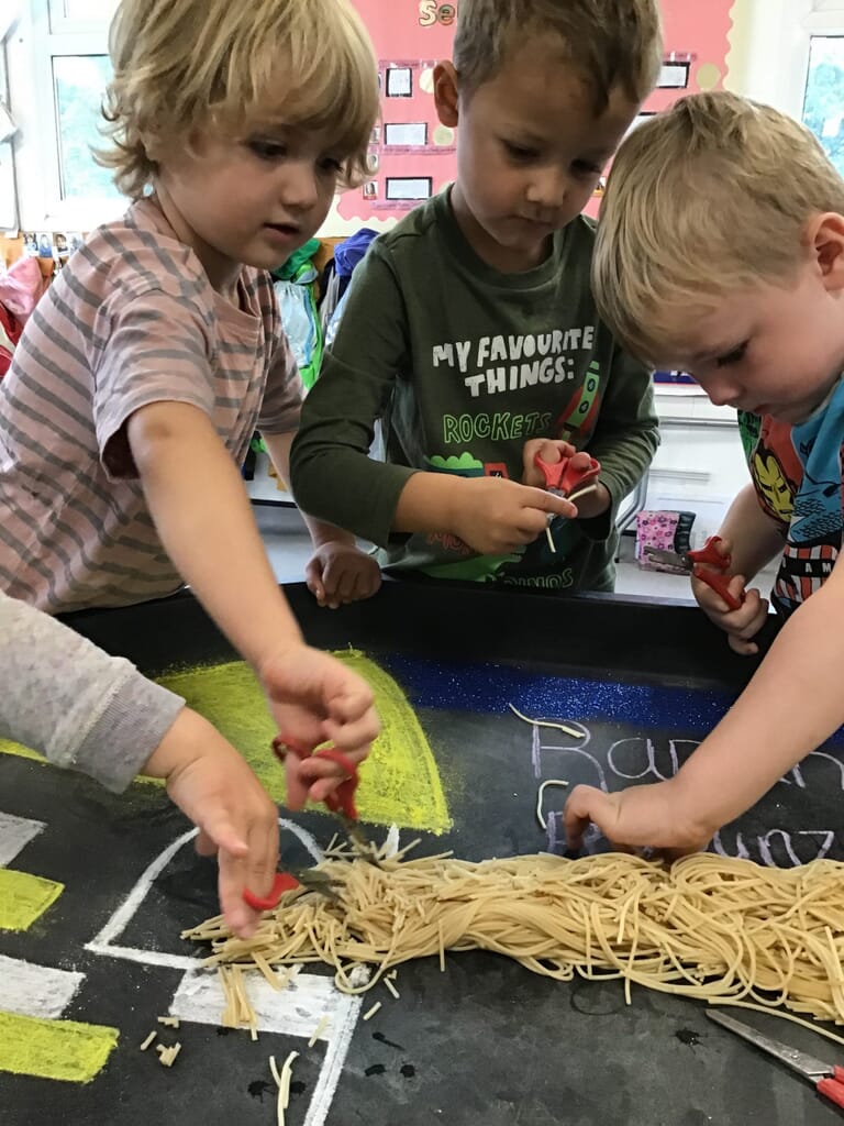 Nursery children cutting spaghetti