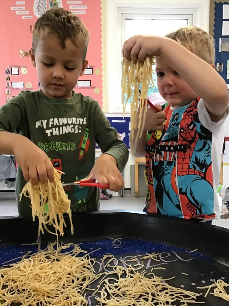 Nursery children cutting spaghetti