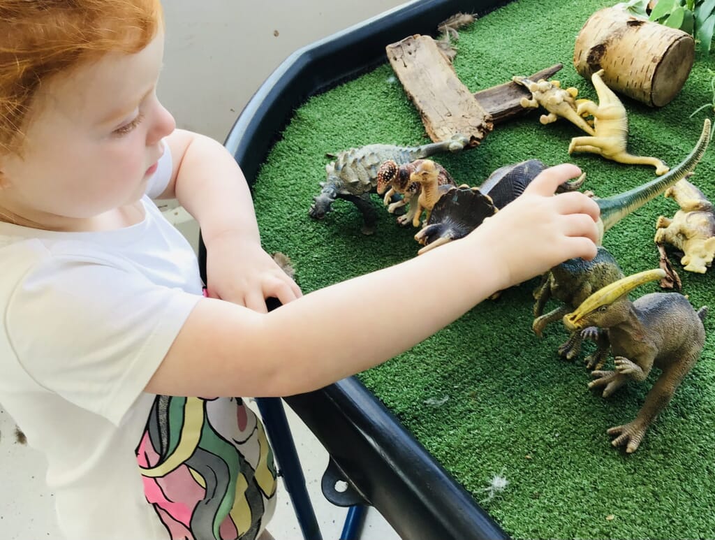 Nursery child playing with dinosaurs