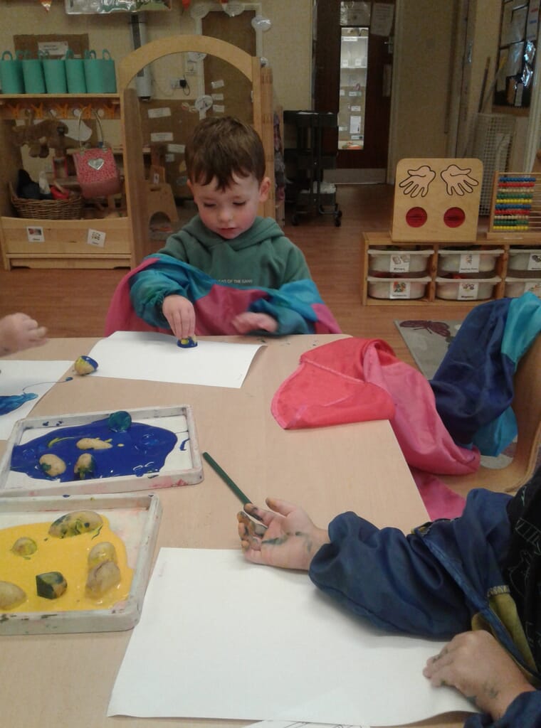 Nursery children painting with sponges