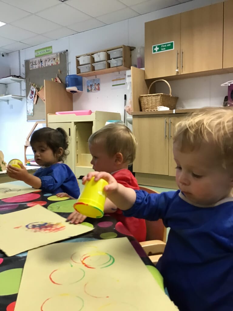 Nursery children painting with cups