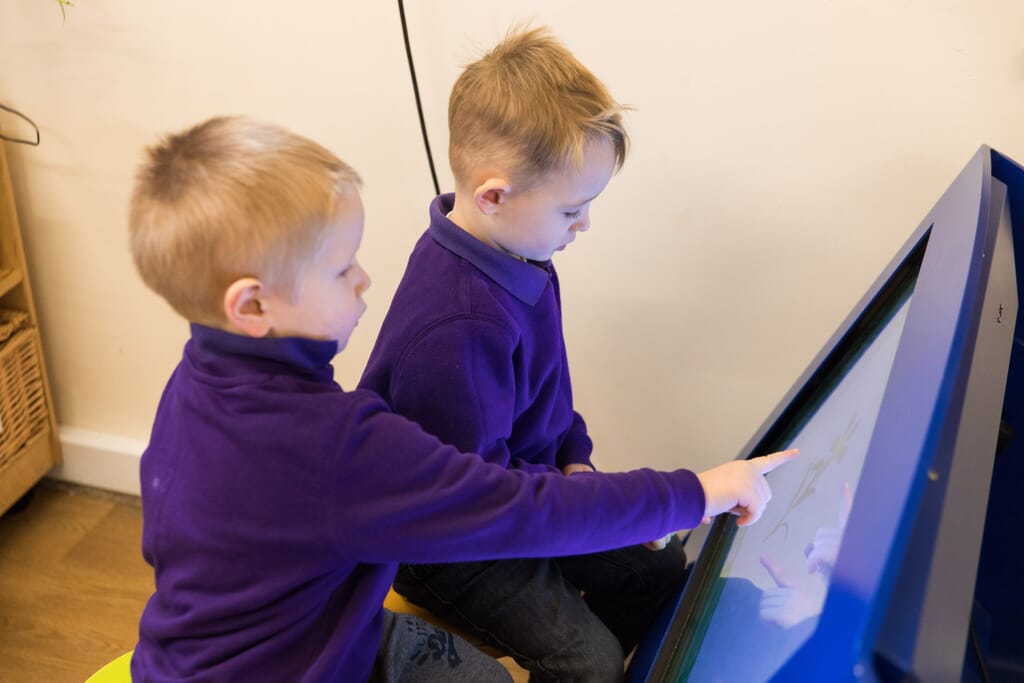Boys playing on nursery digital tablets