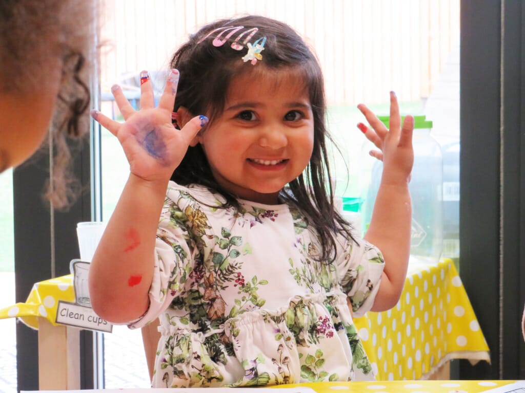 Young girl holding up paint hands