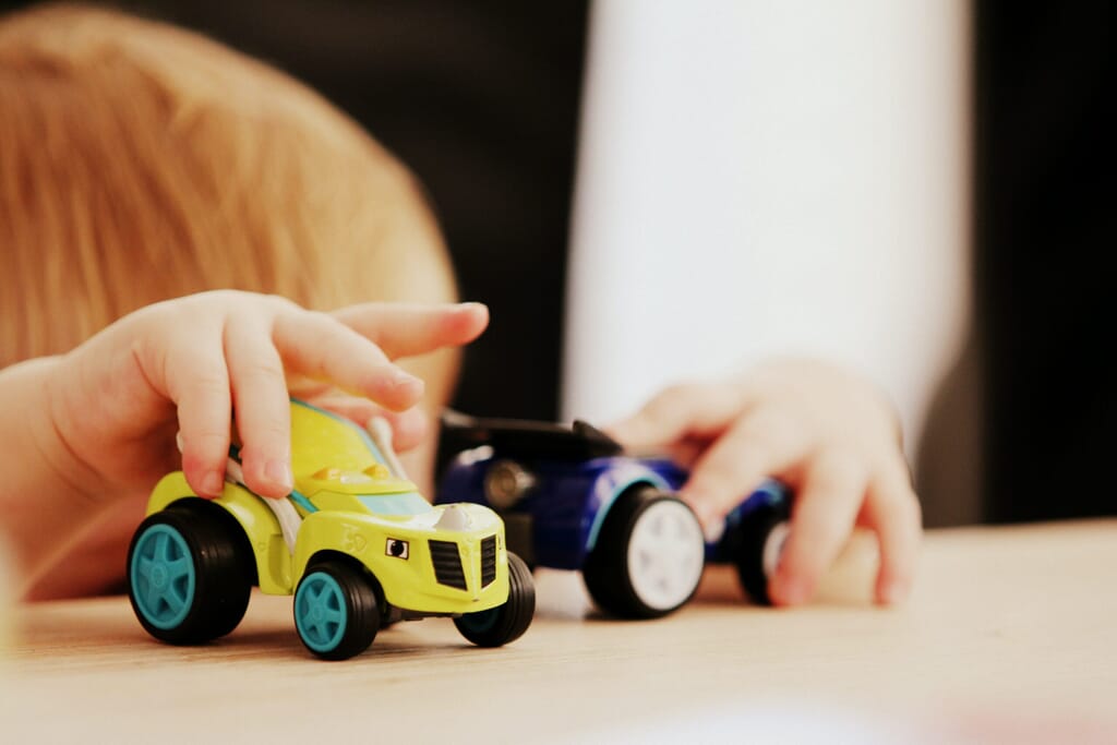 Nursery child playing with toy cars
