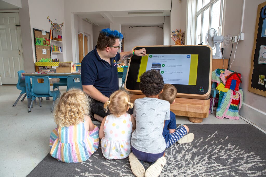 Children and team looking at digital table in nursery