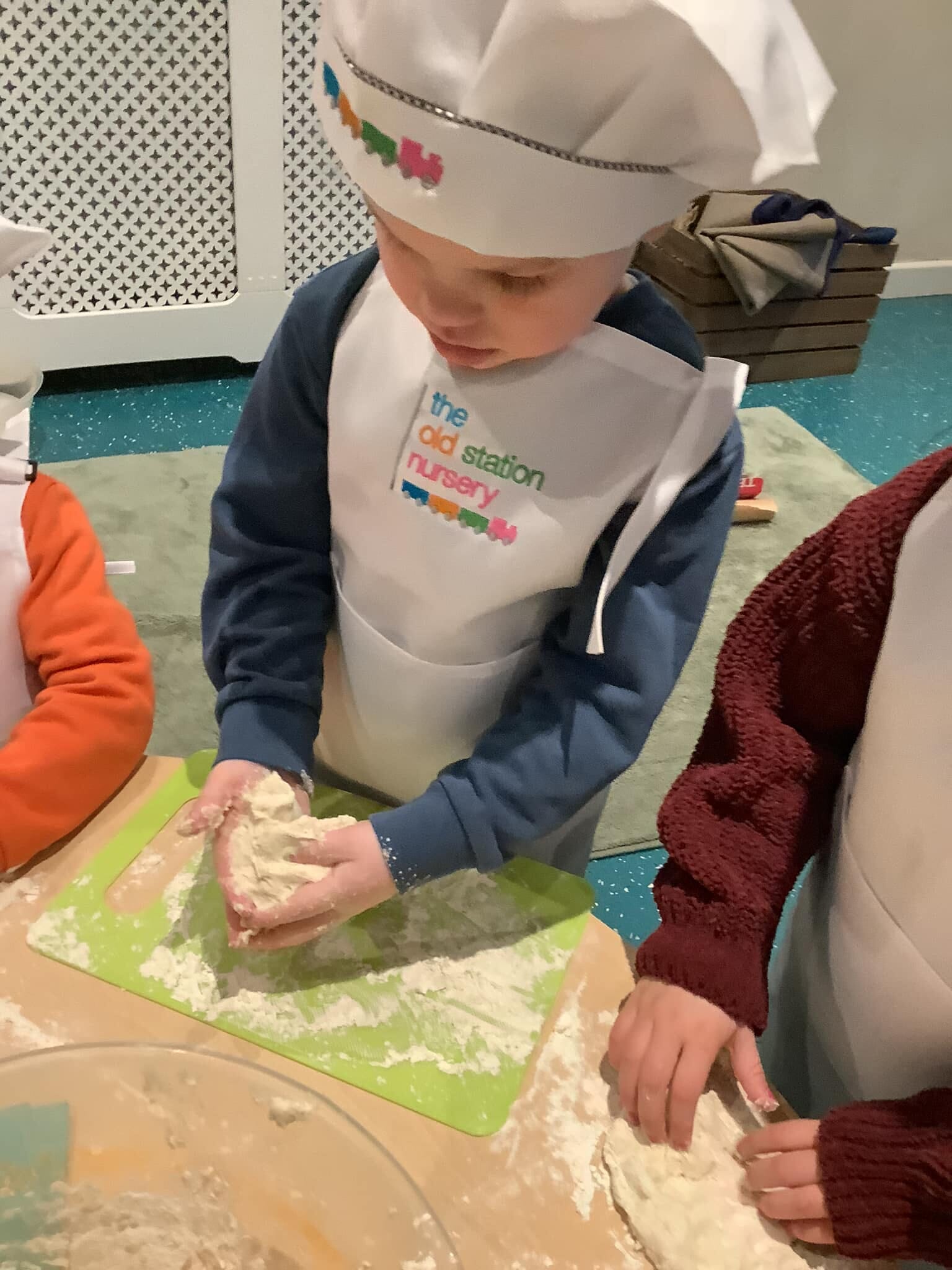 Child preparing food in a branded chef's hat and apron
