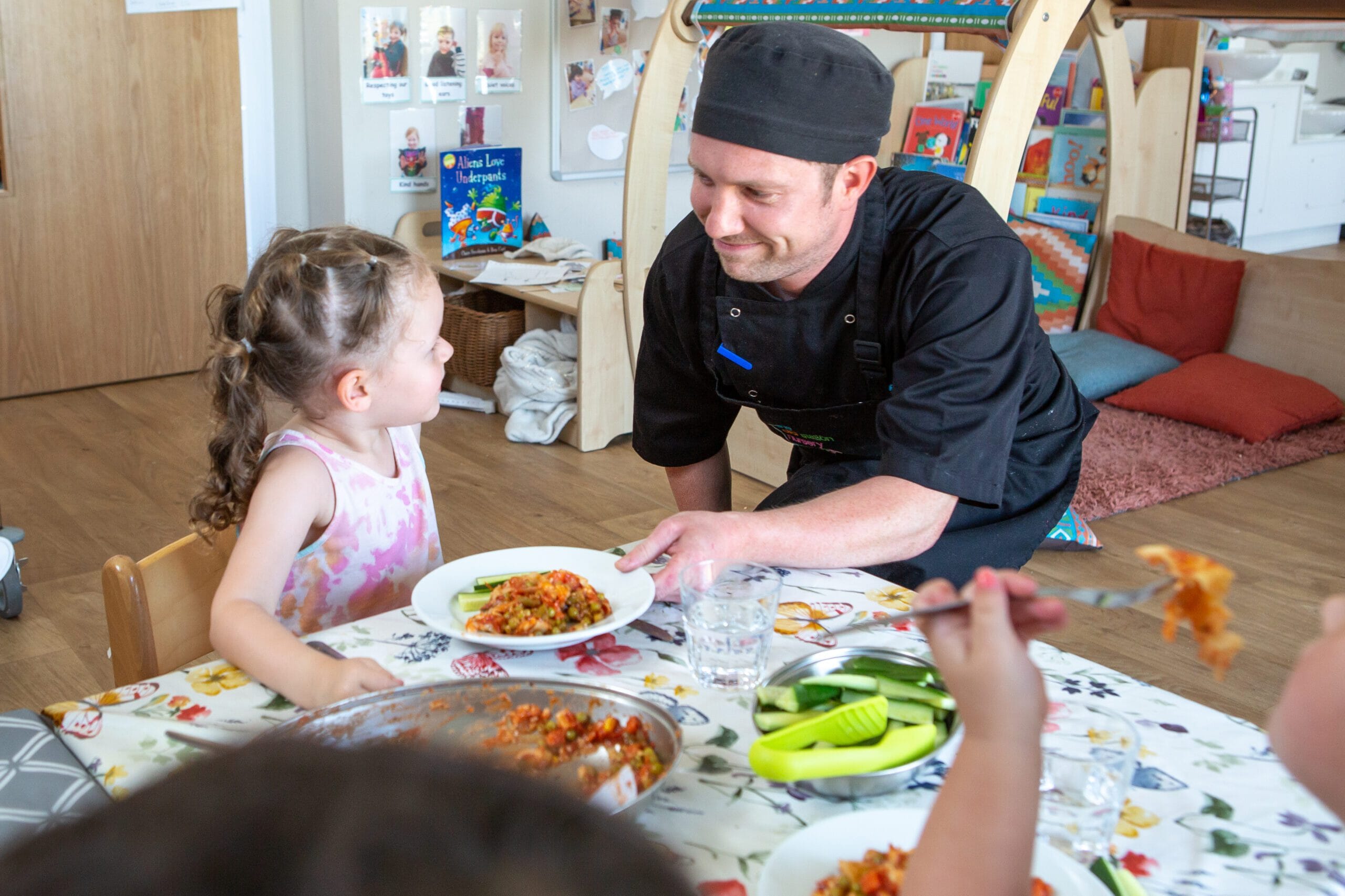 Nursery Chef handing food to child at the dining table