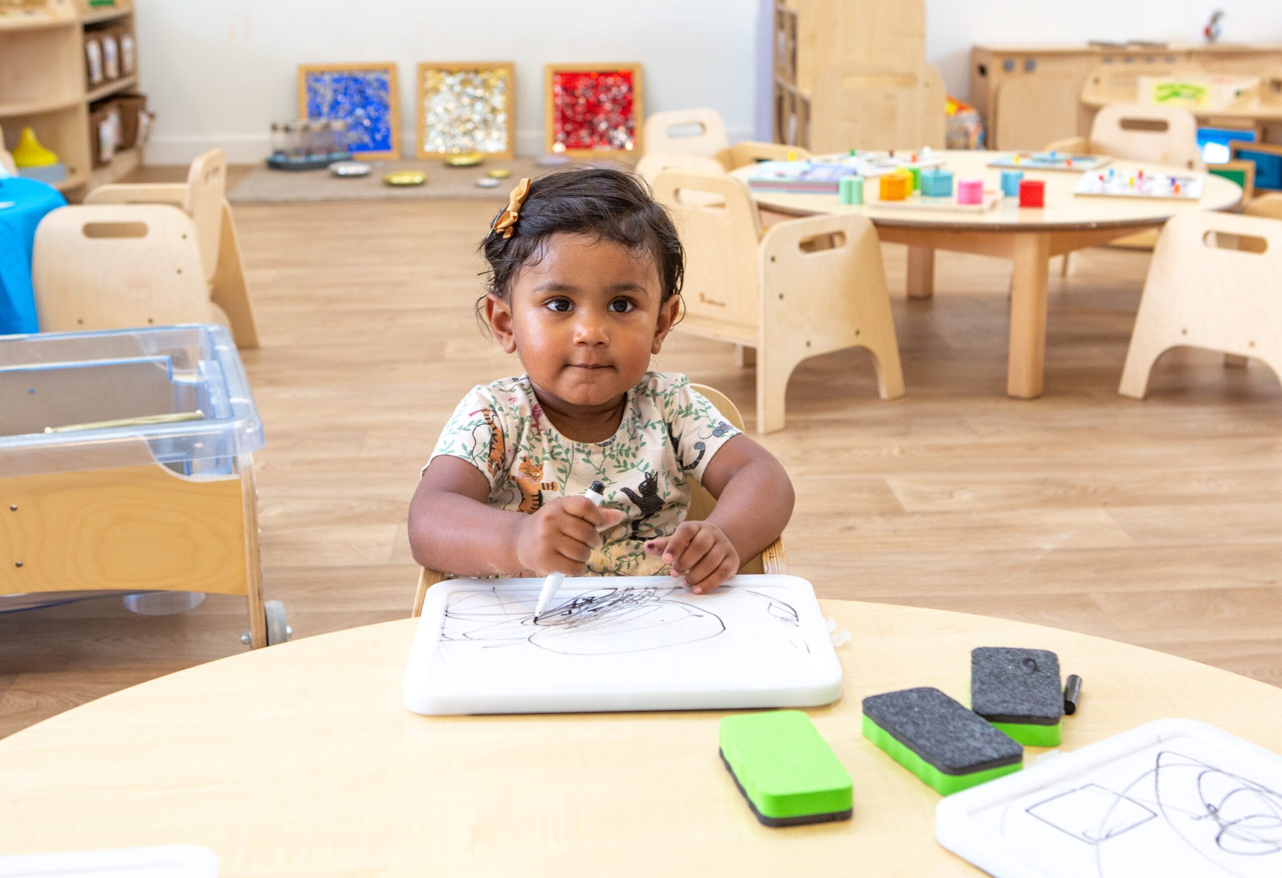 Child at a table in nursery holding a pencil