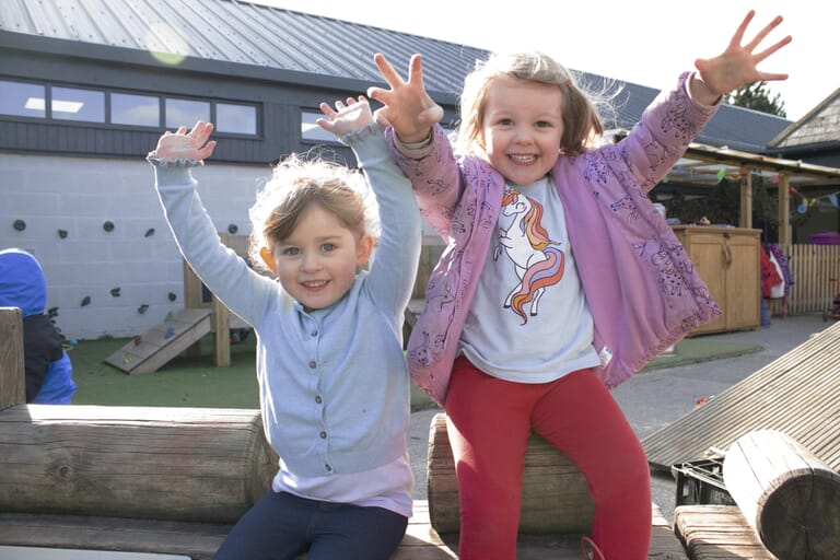 Two young girls smiling and laughing with their hands in the air