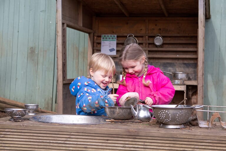 Children playing with natural resources at the mud kitchen in Forest School