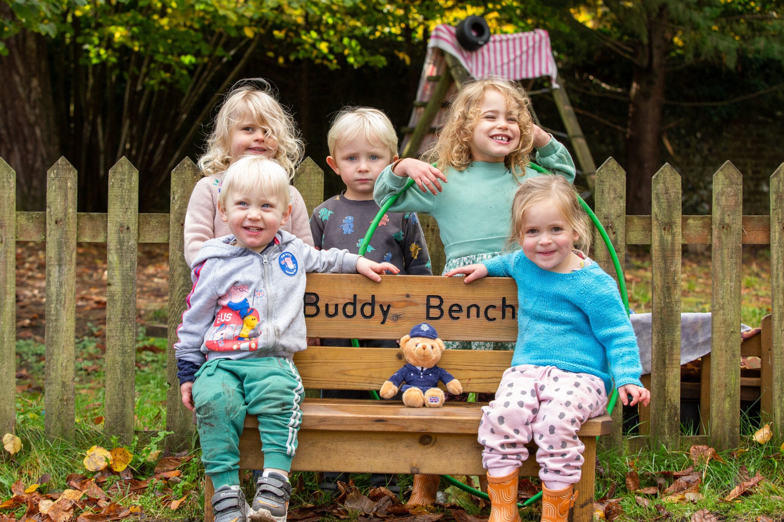 Children sitting on the 'Buddy Bench' at nursery with PC Paws
