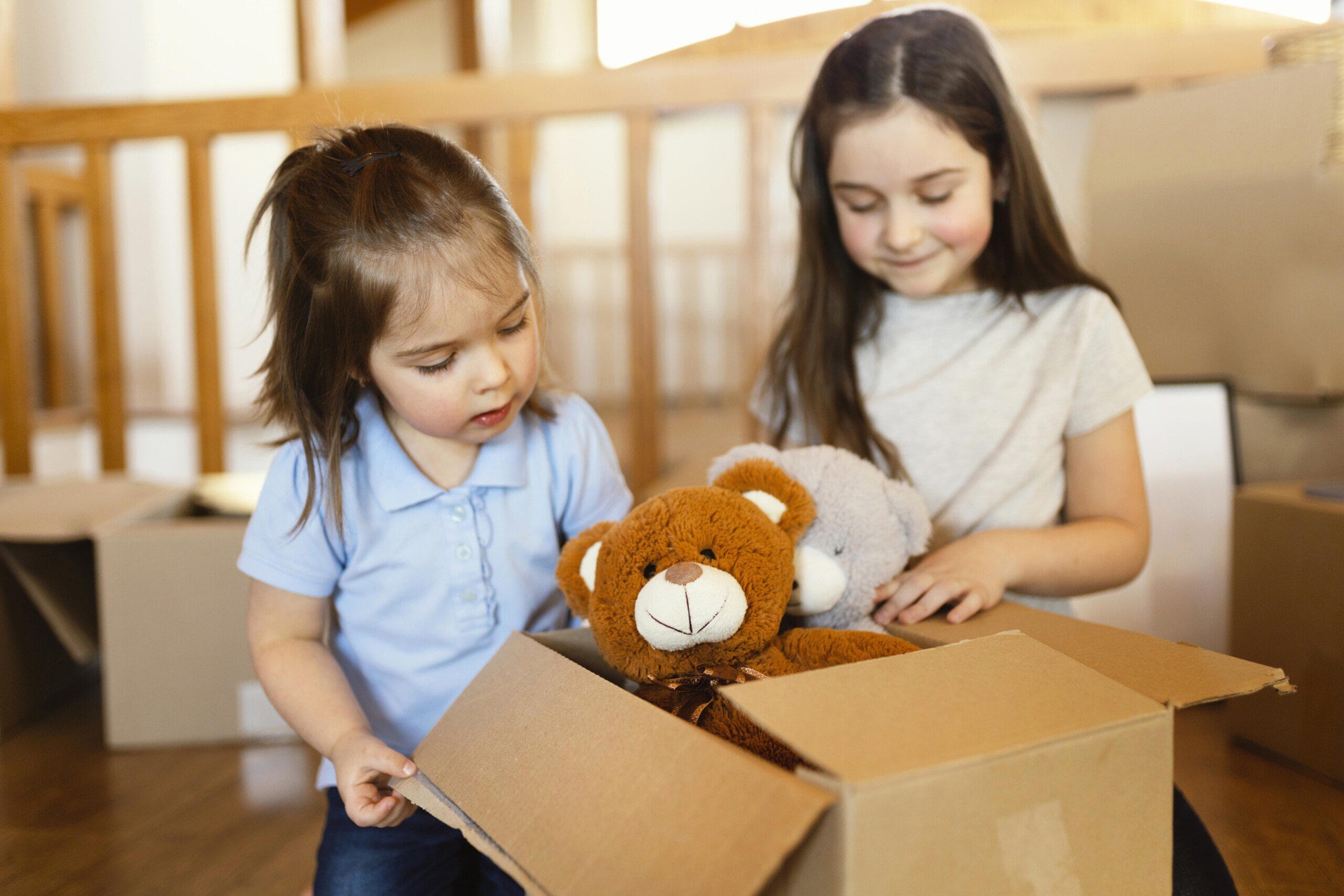 Two children packing a box with items to donate