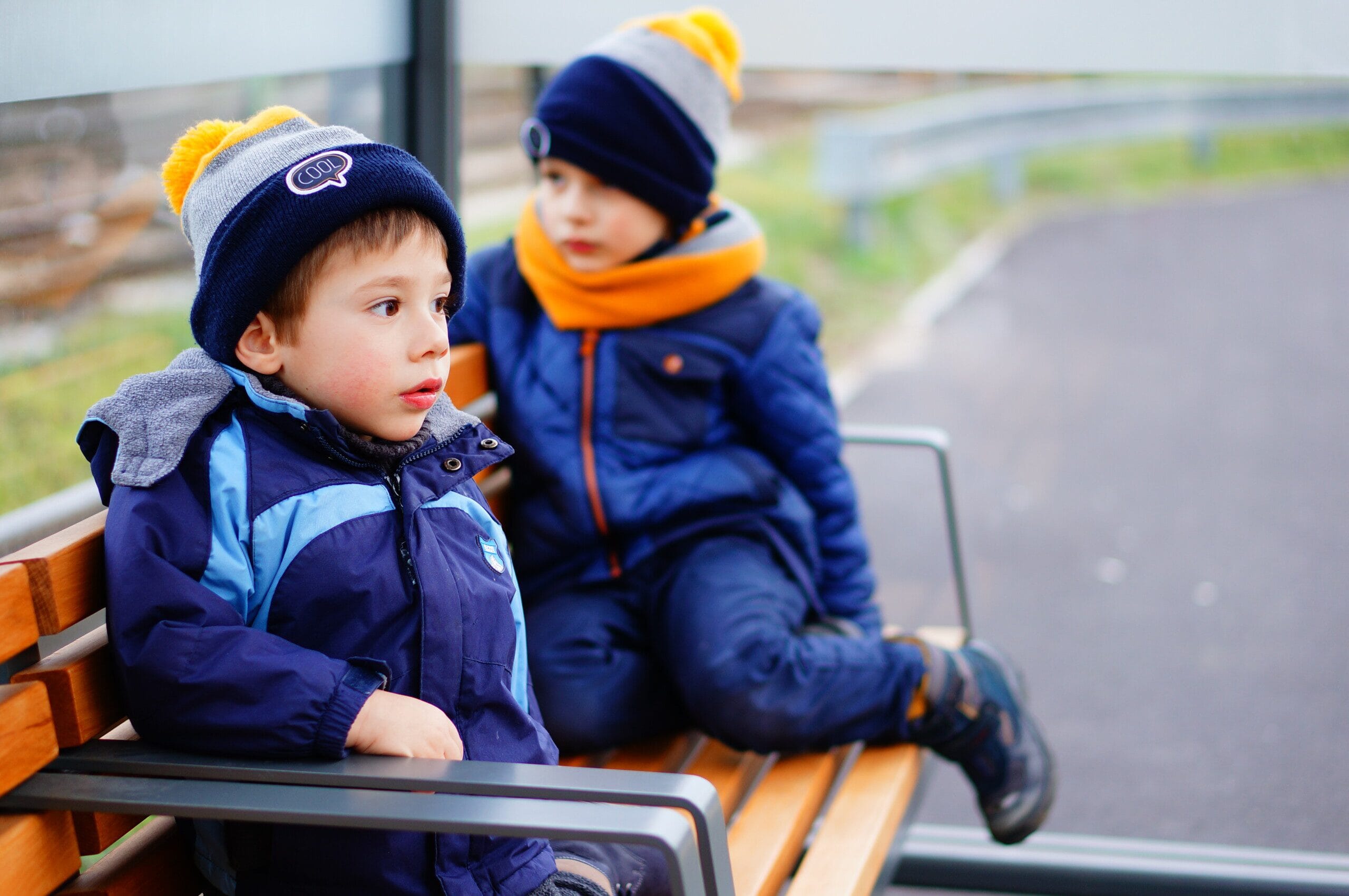 Two children sitting at a bus stop 
