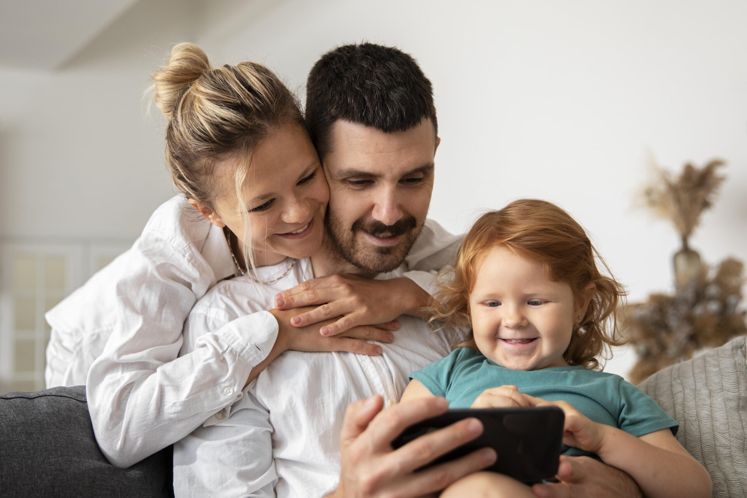 medium-shot-smiley-parents-kid-with-phone