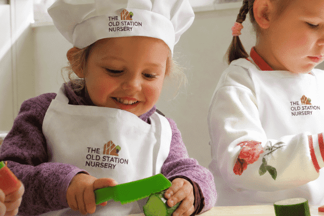 Young girl cutting cucumber at nursery